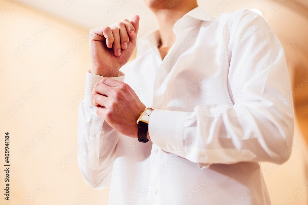 Obraz premium man fastens the cuffs on his white shirt. Close
