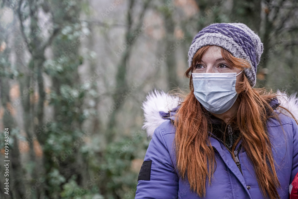 Smiling redhead woman Relaxing In Nature With Protective Face Mask