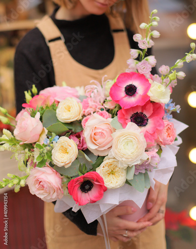 Floral bunch in round box. Bouquet in bright color of beautiful Mixed flowers. Excellent garden flowers in the arrangement   the work of a professional florist. Gift box in florist hands