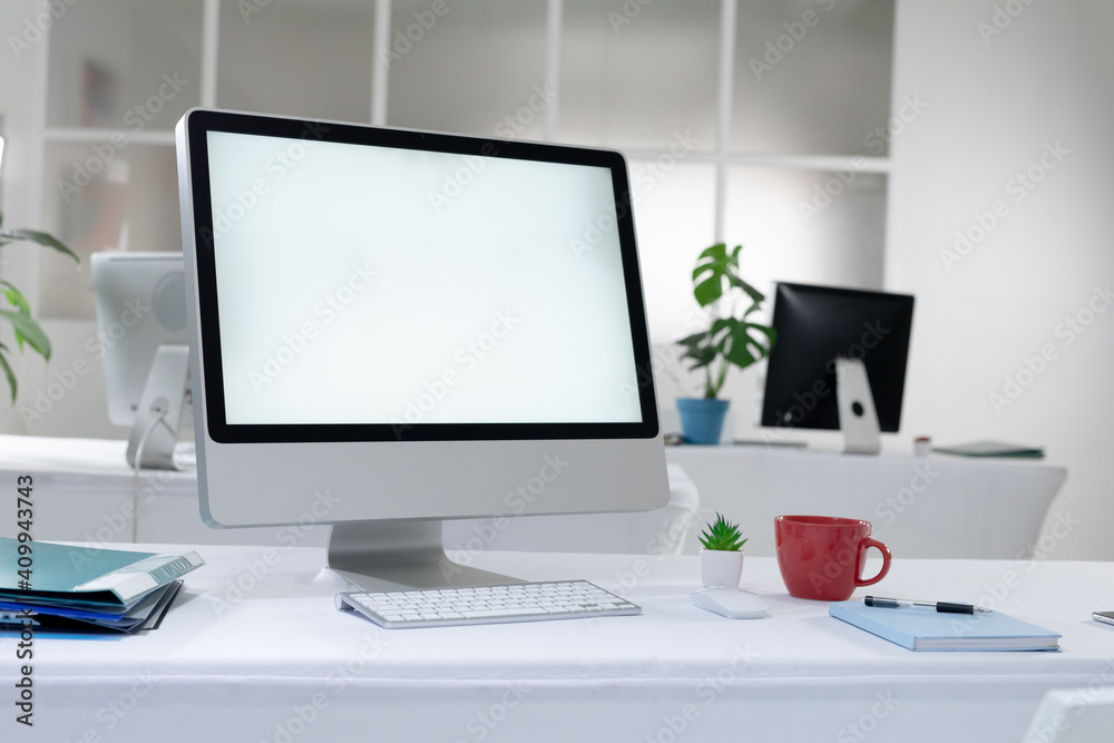 Fototapeta premium Desktop computer with illuminated screen and cup at workstation in abandoned office