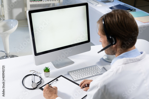 Caucasian male doctor making consultation video call using computer and headset