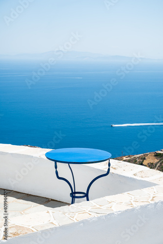 Fototapeta Naklejka Na Ścianę i Meble -  Aegean sea view from a balcony with a simple blue table while a speedboat passes. Sifnos, Greece.