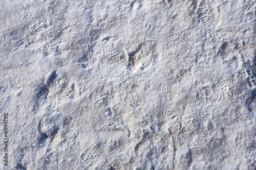 Prints on a snowy road, close-up. Abstract background texture of snow and snow layers.