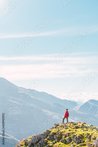 Back view of anonymous explorer standing on green rock and admiring picturesque landscape of mountains in El Mazuco photo