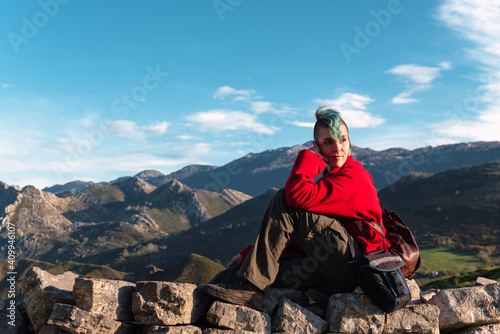 Side view of tranquil explorer sitting on rocks on trail while having break during hiking in highlands in El Mazuco and looking away photo