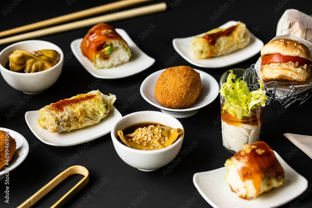 Top view of various tasty fusion food arranged on black table in restaurant Top view of various tasty fusion food arranged on black table in restaurant