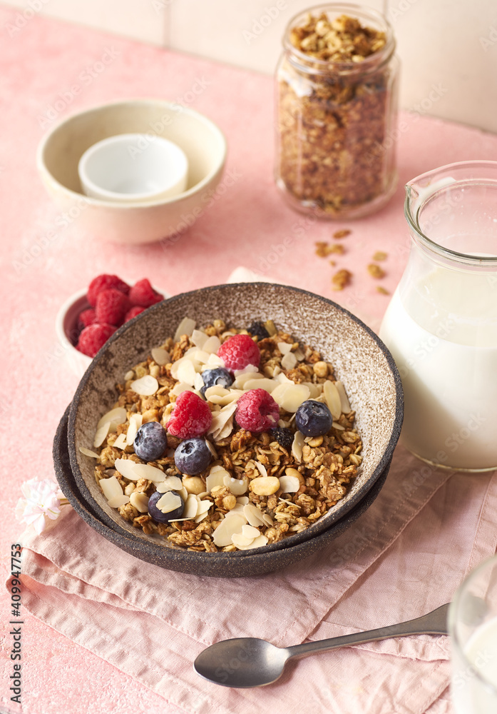 A bowl of granola with nuts and oats served with berries and milk A bowl of granola with nuts and oats served with berries and milk