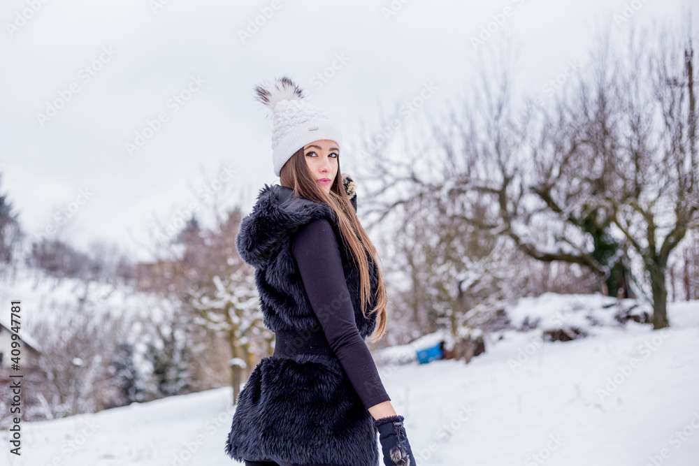 A beautiful smiling girl in black clothes and a white knitted hat in winter A beautiful smiling girl in black clothes and a white knitted hat in winter