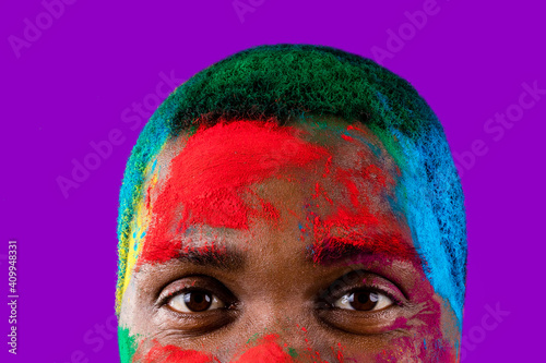 latin brazilian male in white cotton t-shirt with colorful paint of face laughing studio © yurakrasil