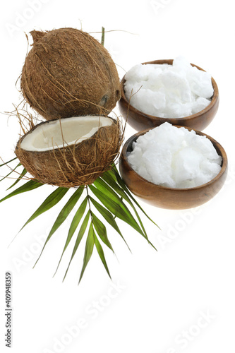 Coconut organic pure oil. Coconut oil in a wooden cup and coconuts fruits close-up with green leaf isolated on white background