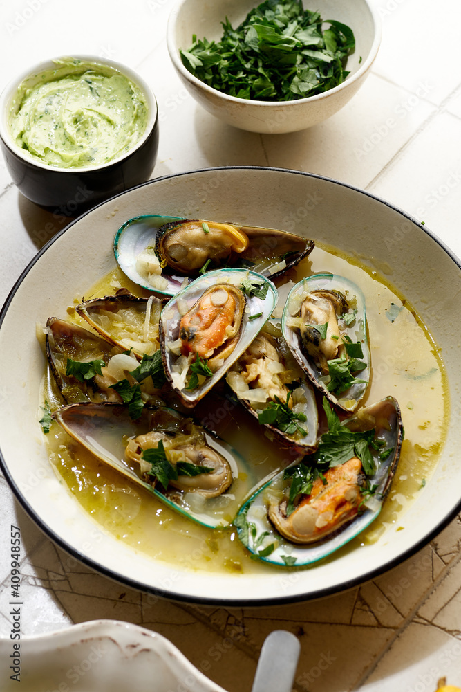Cooked kiwi green mussels with wine, garlic and parsley served with baguette and butter with herbs Cooked kiwi green mussels with wine, garlic and parsley served with baguette and butter with herbs