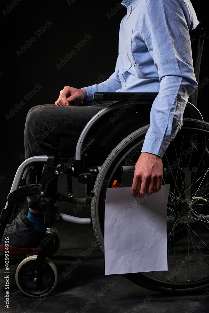 Obraz premium handicapped upset male sits with job search paper down, unhappy and hopeless. no social life and support. cropped man sitting on wheelchair