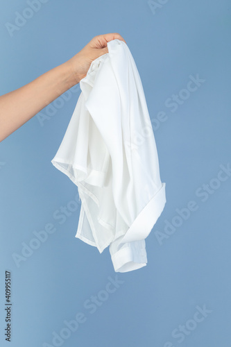 hand holding a white silk textile, blue background empty space for text
