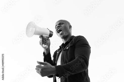 From below of African American male shouting in loudspeaker while standing on white background