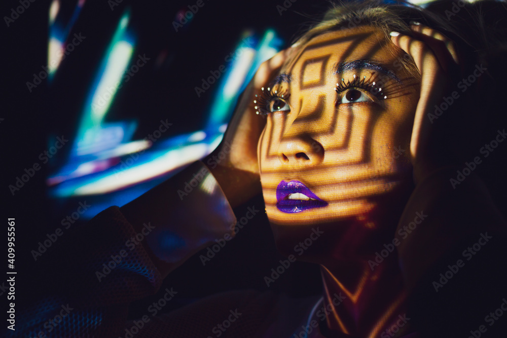 © Edsanca/ADDICTIVE STOCK - Asian female model with creative makeup standing in studio illuminated by colorful projector lights and looking away while touching head © Edsanca/ADDICTIVE STOCK - Asian female model with creative makeup standing in studio illuminated by colorful projector lights and looking away while touching head