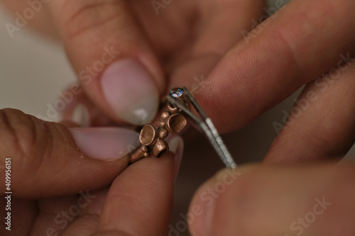 Macro shot. Craft jewelery making. Ring repairing. Putting the diamond on the ring. Desktop for craft jewellery making with professional tools.