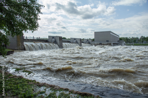 Hochwasser an Staustufe bei einem Elektrizitätswerk - alle Schleusen sind offen und der Fluß ist überschwemmt, Wolken am Himmel photo