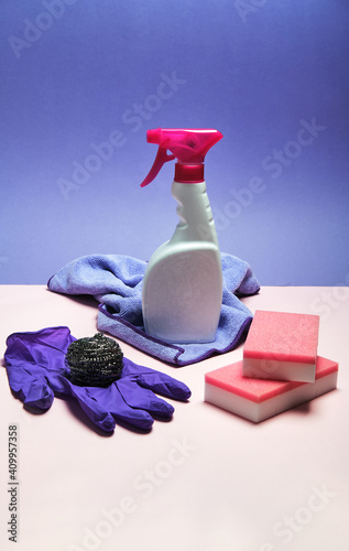 Top view of latex gloves and spray detergent arranged on pink and blue background with sponges and rag for cleaning concept