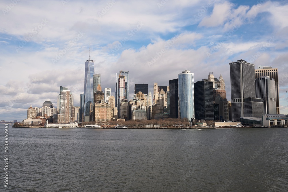 Cityscape of Manhattan with high rise buildings with glass exterior under blue cloudy sky in New York Cityscape of Manhattan with high rise buildings with glass exterior under blue cloudy sky in New York