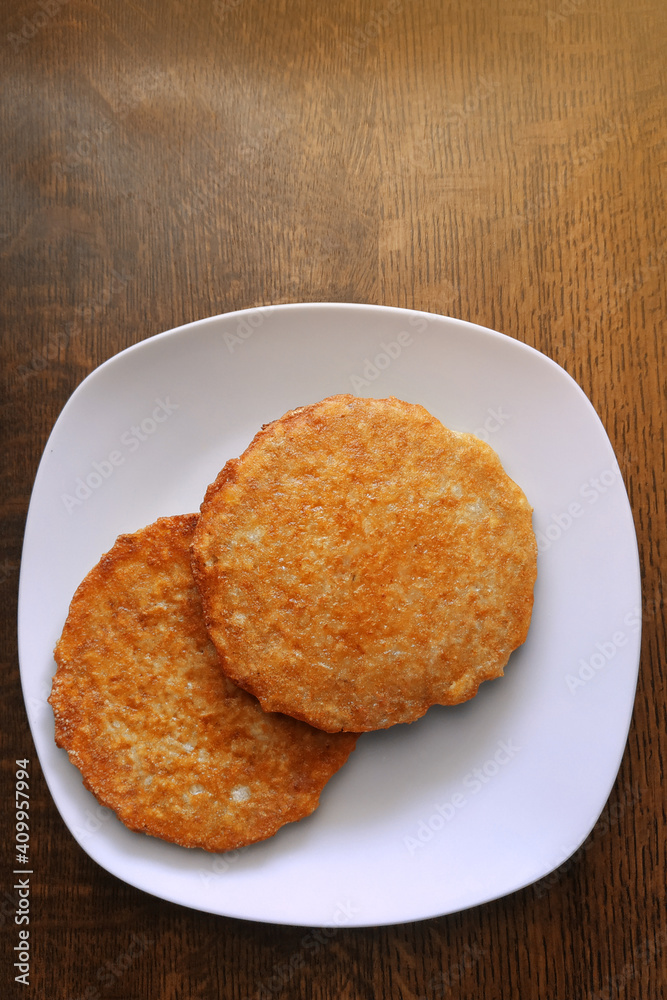 Potato pancakes on a white plate, fatty and unhealthy food, high-calorie and delicious dish. Potato pancakes on a white plate, fatty and unhealthy food, high-calorie and delicious dish.