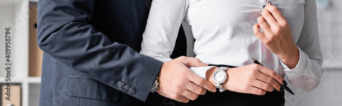 cropped view of businessman touching hand of secretary while seducing her in office, banner