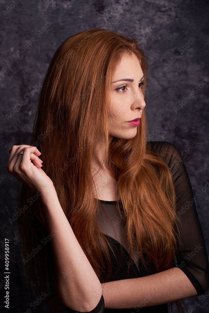 Calm female model in stylish clothes standing in studio with red hair and looking away Calm female model in stylish clothes standing in studio with red hair and looking away