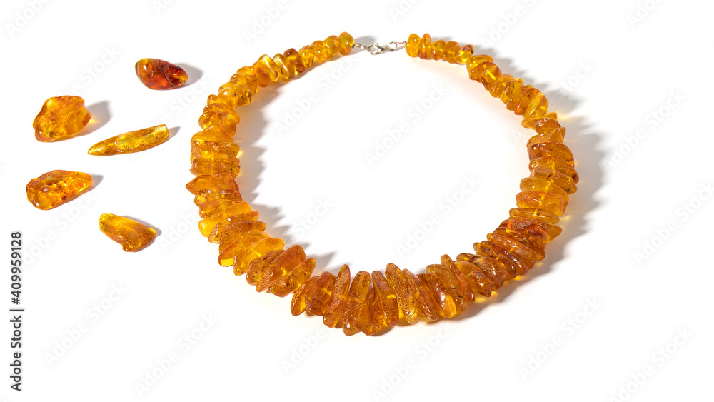 Obraz premium Sparkling transparent orange old Baltic amber necklace on a white background. Isolated amber jewelry and amber stones. Ancient amber is healing, powers, strength, love, protection and amulet. 
