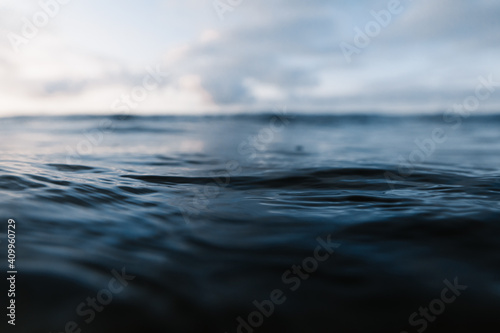 Powerful foamy sea waves rolling and splashing over water surface against cloudy blue sky photo