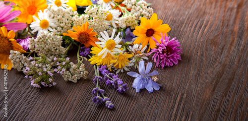 Flowers on old grunge wooden table (chamomile lupine dandelions thyme mint bells rape). Wild nature background