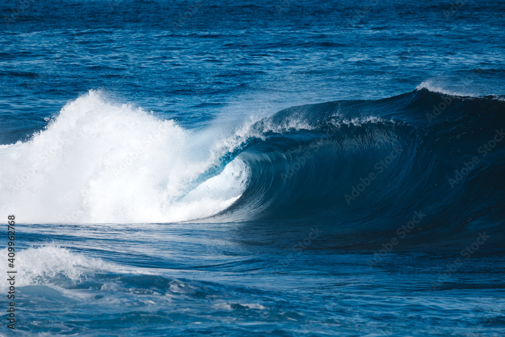 Powerful foamy sea waves rolling and splashing over water surface against cloudy blue sky Powerful foamy sea waves rolling and splashing over water surface against cloudy blue sky