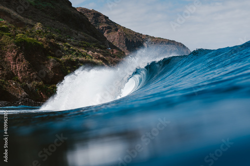 Powerful foamy sea waves rolling and splashing over water surface against cloudy blue sky