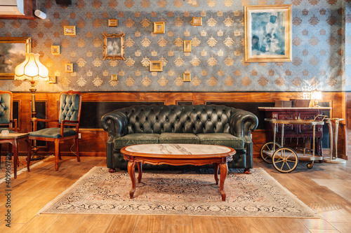 Comfortable vintage interior of spacious hall of restaurant with stylish armchairs and sofa under crystal chandeliers