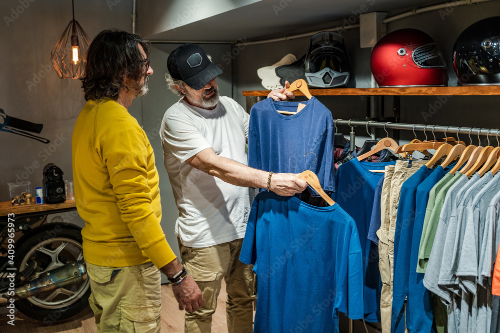 © Javier De La Torre/ADDICTIVE STOCK - Side view clothing store owner helping new customer to choose a shirt © Javier De La Torre/ADDICTIVE STOCK - Side view clothing store owner helping new customer to choose a shirt