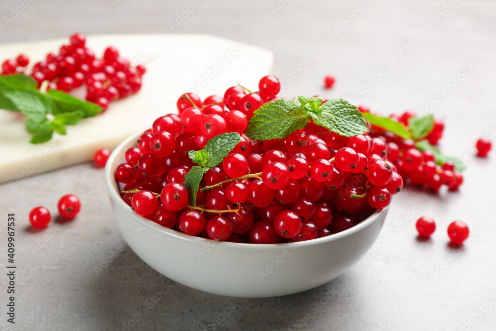 Delicious red currants and mint in bowl on light grey table Delicious red currants and mint in bowl on light grey table