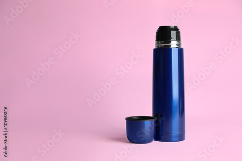 Stylish thermo bottle on pink background, space for text