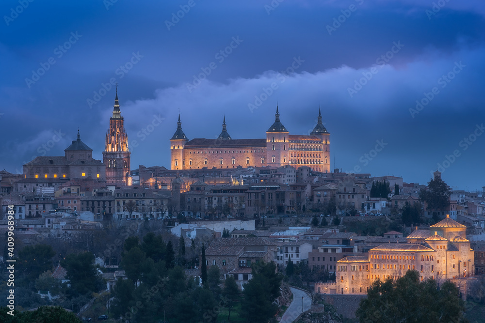 Aerial view of old city with historic buildings and stone castle on hill against cloudy sky during sunset in Toledo, Spain Aerial view of old city with historic buildings and stone castle on hill against cloudy sky during sunset in Toledo, Spain