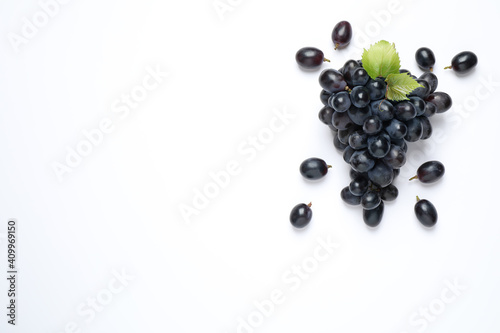 Bunch of dark blue grapes with leaves on white background, top view