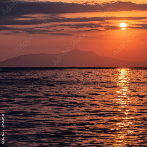 orange fiery sunrise sky with some clouds over calm sea  nature background.