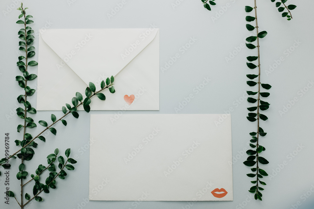 Minimal composition with a white envelope, heart and green leaves Minimal composition with a white envelope, heart and green leaves