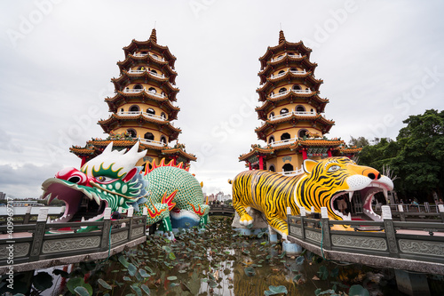 Low angle exterior of traditional oriental pagodas with colorful ornamental Tiger and Dragon sculptures built on lake and connected with shore by stone bridges in Kaohsiung city in Taiwan photo