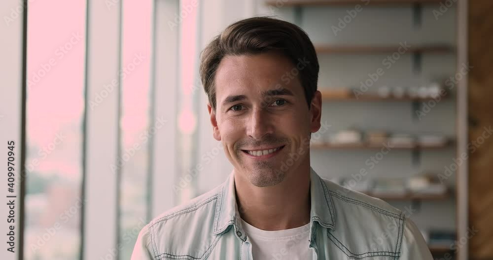 Head shot smiling handsome young 35s male employee manager worker entrepreneur looking at camera, posing alone at modern office. Confident caucasian businessman holding video call, listening partner. Head shot smiling handsome young 35s male employee manager worker entrepreneur looking at camera, posing alone at modern office. Confident caucasian businessman holding video call, listening partner.