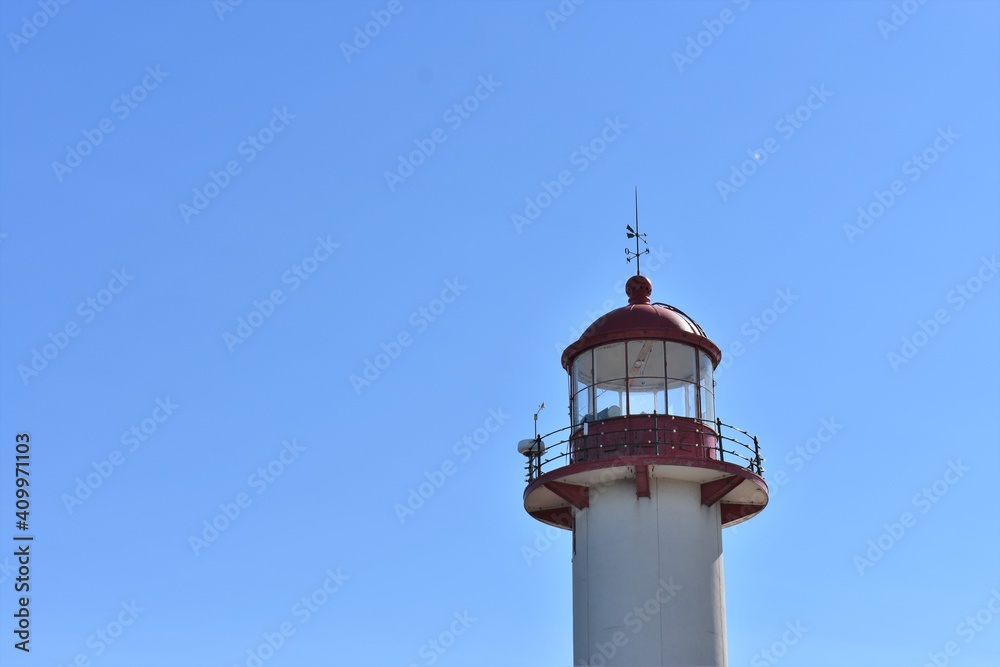 top of red and white lighthouse in the blue sky