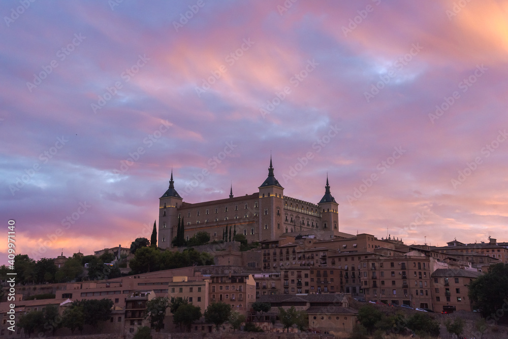 Aerial view of old city with historic buildings and stone castle on hill against cloudy sky during sunset in Toledo, Spain Aerial view of old city with historic buildings and stone castle on hill against cloudy sky during sunset in Toledo, Spain