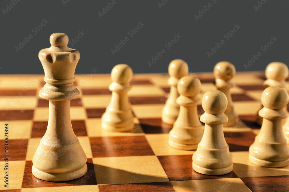 Queen and pawns on wooden chess board, closeup. Social roles concept Queen and pawns on wooden chess board, closeup. Social roles concept