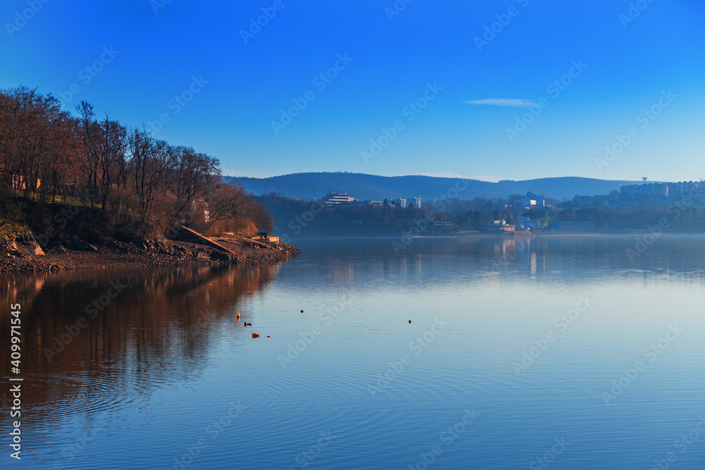 Brno Dam Czech Republic Europe. Water surface and dam. In the background is the housing estate Bystrc and Kohoutovice. The sky is blue with white clouds