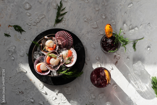 Top view of tasty oriental dish made of clams with herbs served on table with glasses of refreshing cocktails garnished with dried oranges