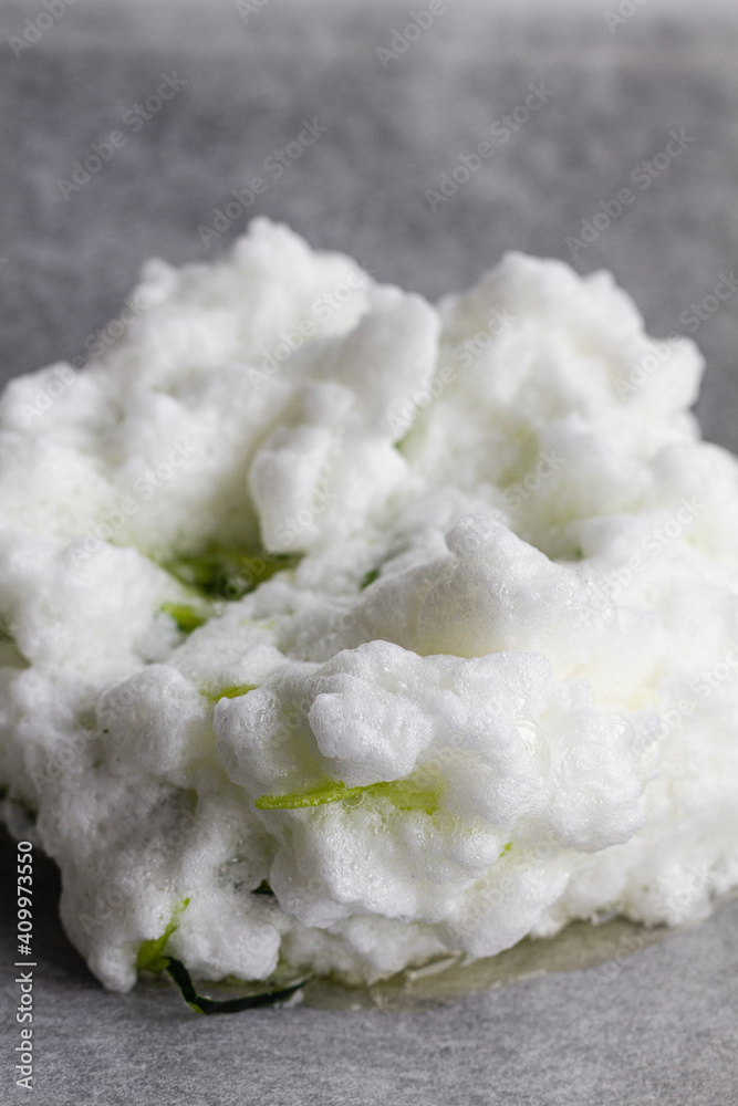 Closeup of portion of unbaked whipped egg whites mixed with fresh green zucchini on baking paper before putting to oven Closeup of portion of unbaked whipped egg whites mixed with fresh green zucchini on baking paper before putting to oven