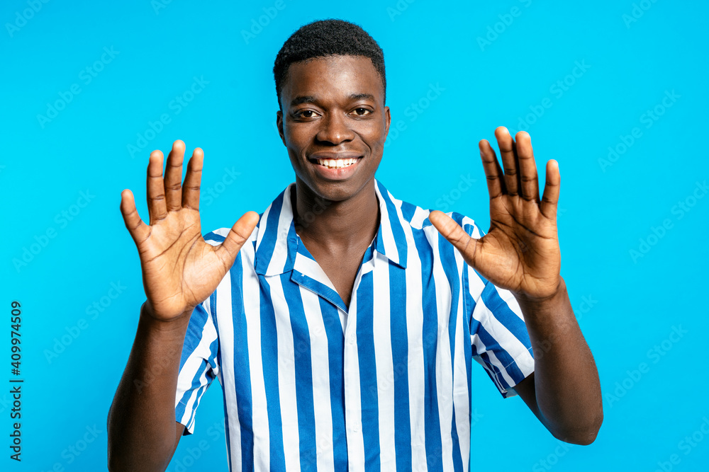 Delighted handsome African American male wearing classic shirt standing on brown background in studio and looking at camera Delighted handsome African American male wearing classic shirt standing on brown background in studio and looking at camera