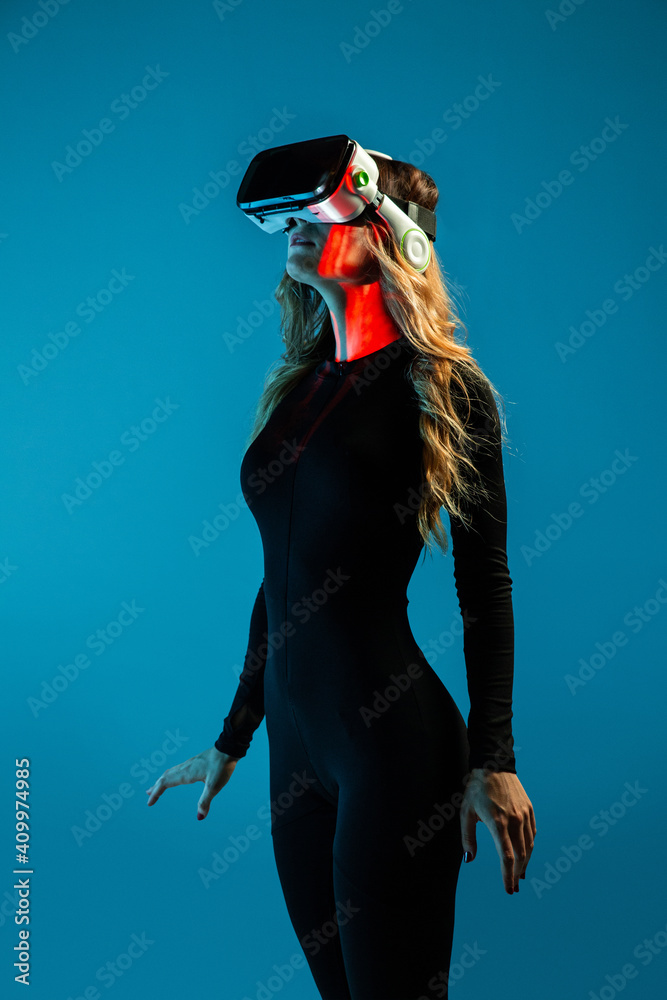 © Manuel Ruiz/ADDICTIVE STOCK - Side view of young unrecognizable blonde woman standing wearing virtual reality headset on colorful blue studio background © Manuel Ruiz/ADDICTIVE STOCK - Side view of young unrecognizable blonde woman standing wearing virtual reality headset on colorful blue studio background