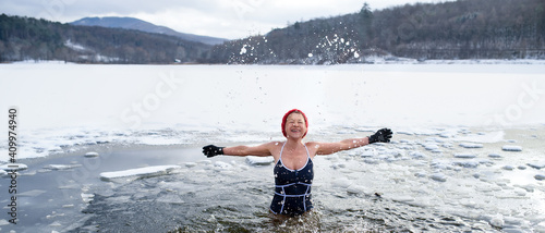 Bild auf Leinwand Front view of active senior woman in swimsuit outdoors in water in winter, cold therapy concept
